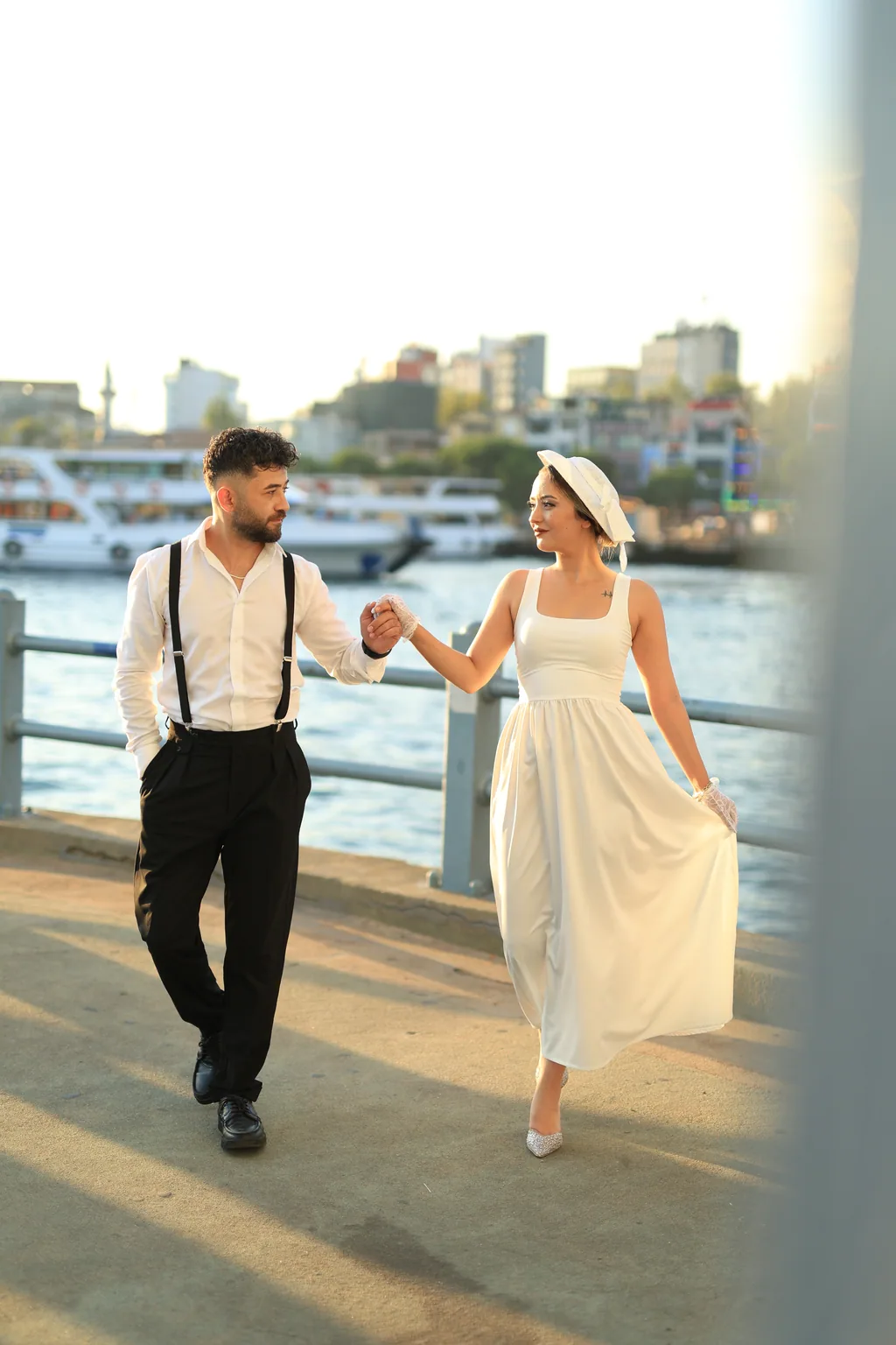 Gelin ve damat, Boğaz kıyısında akşam ışığında el ele yürüyor.